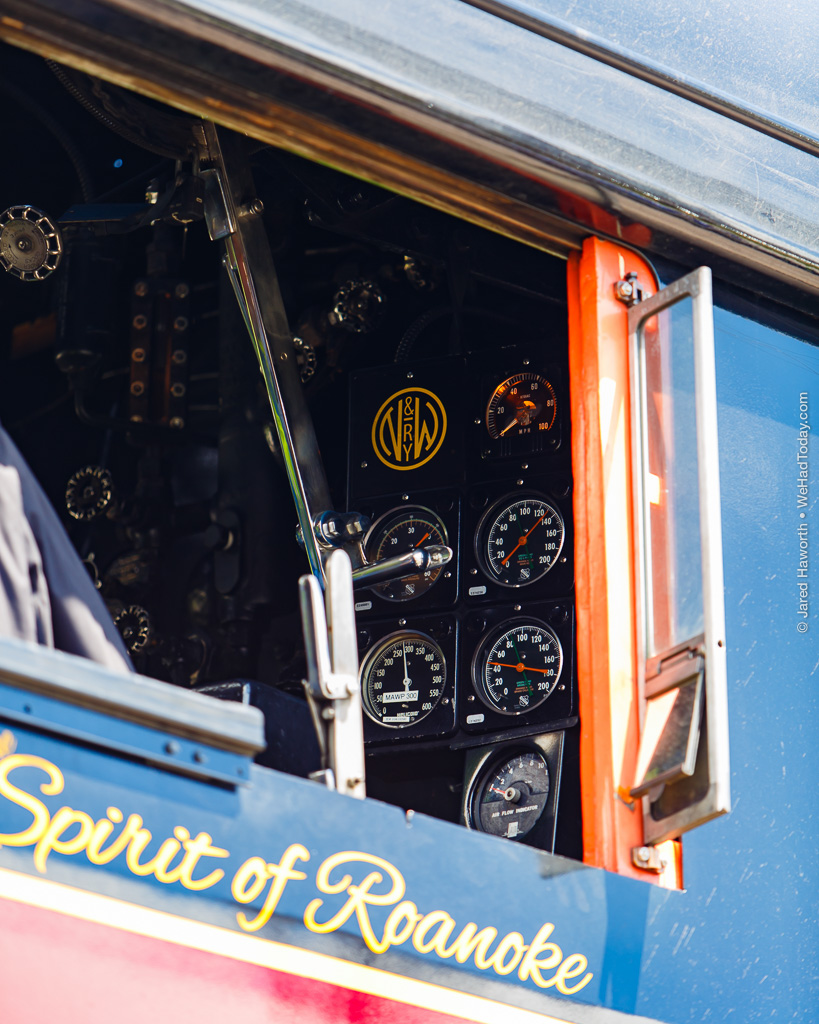 This view into the cab of 611 from trackside in Petersburg reveals the N&W logo, boiler pressure gauges, speedometer, and the polished chrome of the throttle control.