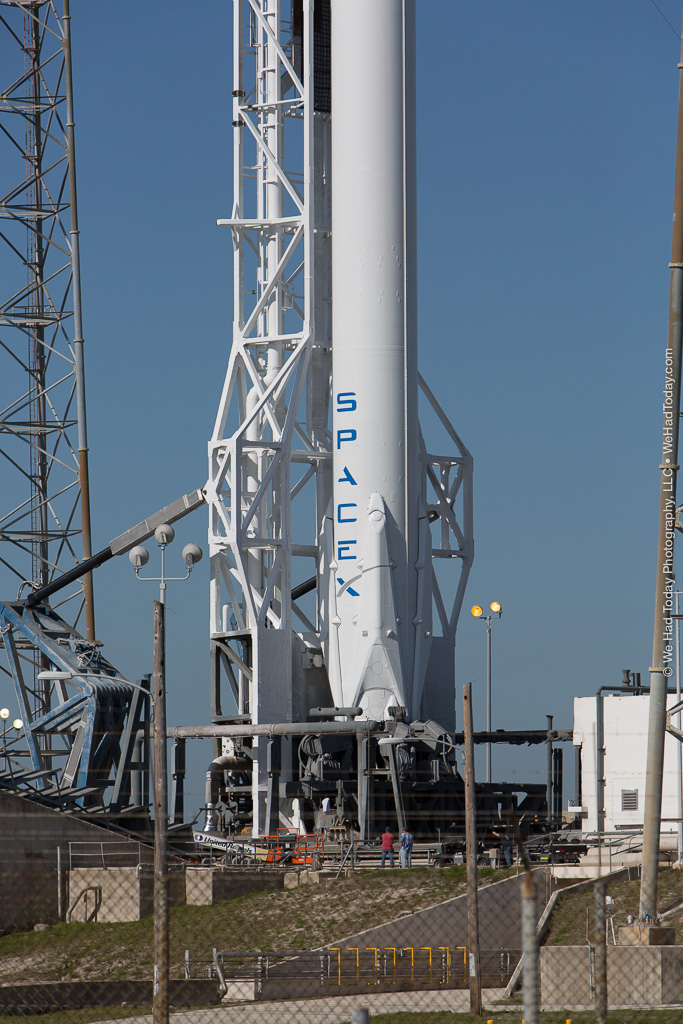 The immense height of the Falcon 9 can be hard to fathom, but the presence of two workers near the base give some sense of scale.